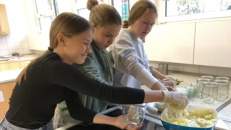 Drei M�dels bef�llen Einmachgl�ser mit Kraut