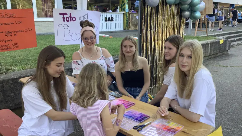 Eine Gruppe Schülerinnen bastelt Armbändchen