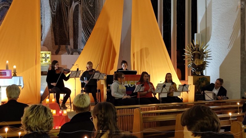 Schüler und Lehrer musizieren mit Geigen, Flöten und Gitarre.